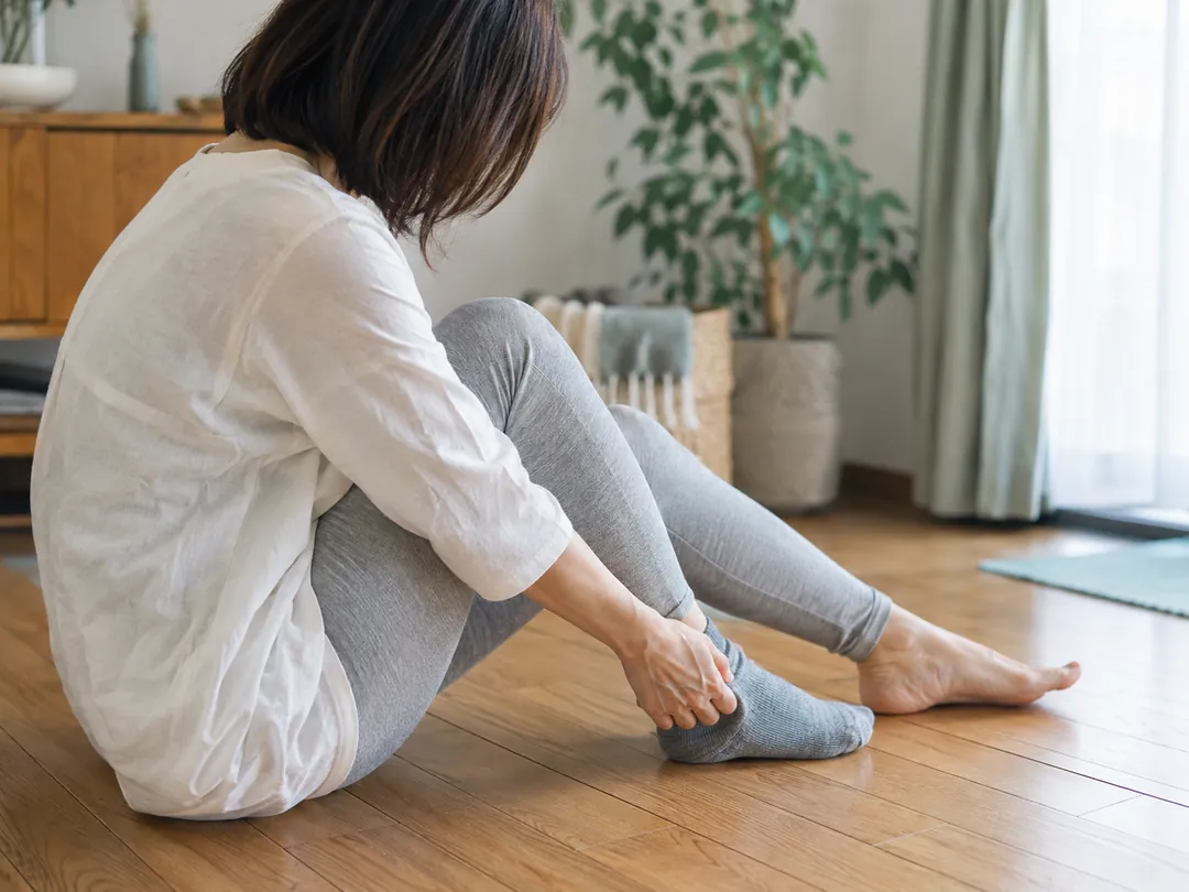 床に座って靴下をはこうとする女性